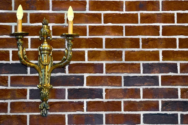 Kırmızı tuğla duvarda çift altın şamdan lambası