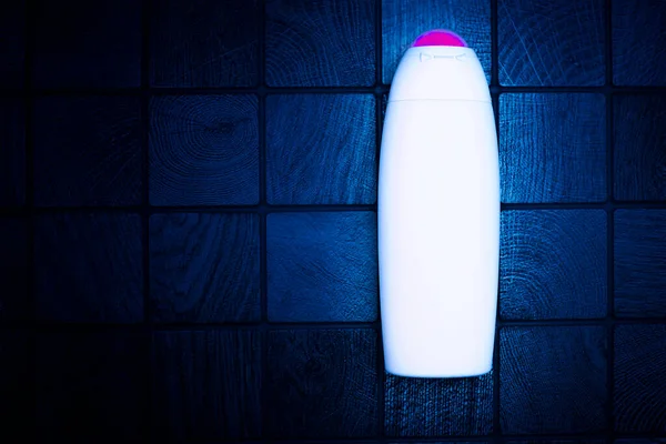 Neon plastic bottle for detergents and shampoos on a checkered dark background — 스톡 사진