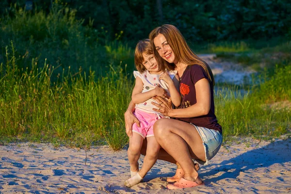 Чудесная симпатичная девочка со счастливой улыбчивой мамой среди песчаных дюн — стоковое фото