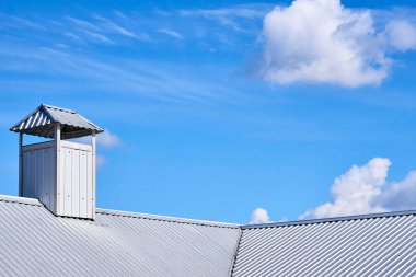 the structure forming the upper covering of a building or vehicle. The roof of the house is covered with a tin profile, a chimney with ventilation. High quality photo