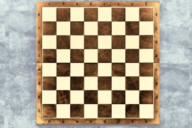 a square board divided into sixty-four alternating dark and light squares, used for playing chess or checkers. Brown dark chessboard on a gray marble surface