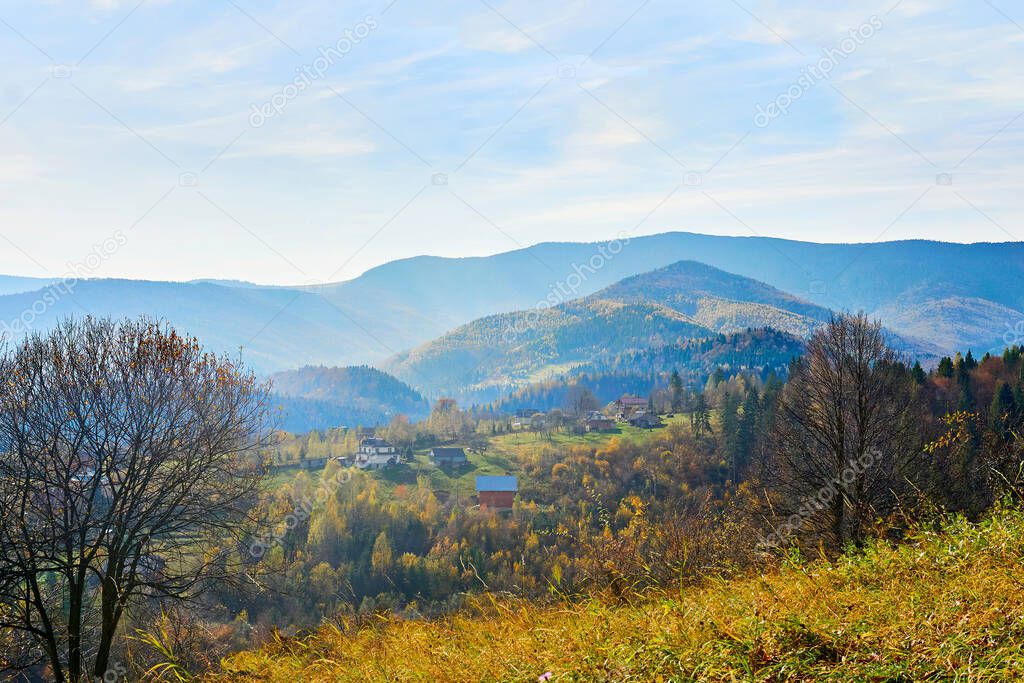 a large natural elevation of the earths surface rising abruptly from the surrounding level, a large steep hill. Distant mountains with blue haze framed by autumn grass.