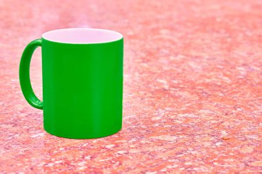 a small bowl-shaped container for drinking from, typically having a handle. Green ceramic cup mug on bright red white spotted background