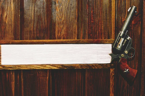 Döner odalı bir tabanca yeniden doldurulmadan birkaç el ateş edilmesine olanak sağlıyor. Açık kahverengi ahşap bir duvarda kovboy tabancası. Mesaj için yer var. Patronun ofisi.