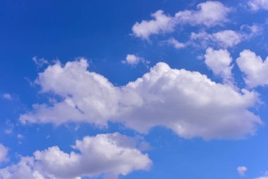 Kabarık beyaz bulutlar gündüz gökyüzüne karşı. Cumulus pamuk yumağı gibi yumuşak bir buluttur.