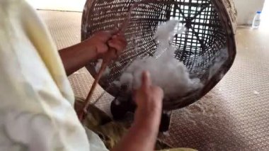 Olgun Asyalı kadınlar Tayland 'da basit bir aletle sepetin içine pamuk dökerler. Yetişkin Asyalı kadın sepete pamuk atıyor.