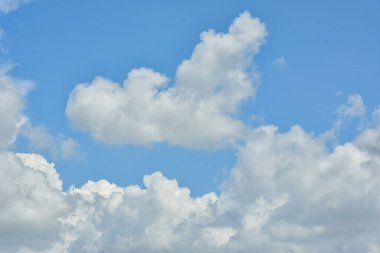 Beyaz bulutlar arka plan için mavi gökyüzüne karşı. Kabarık beyaz bulutlar gündüz gökyüzüne karşı. Cumulus pamuk yumağı gibi yumuşak bir buluttur.