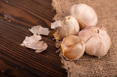 Çuval bezi kaplı bir masada bir sürü genç sarımsak, yakın plan, seçici odaklanma.