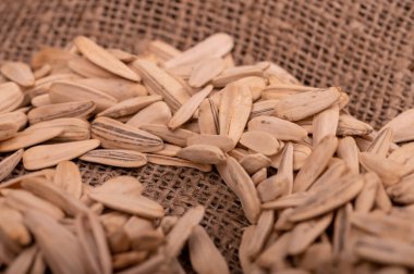 Beyaz ayçiçeği tohumları kaba bir çuval bezinin arka planına saçılmış, yakın çekim seçici odak