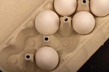Beyaz kartondan yapılmış tepside beyaz tavuk yumurtaları, yakın plan seçici odak.