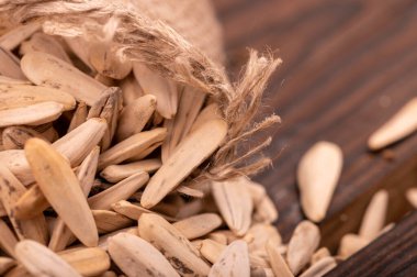 Beyaz ayçiçeği tohumları kaba bir çuval bezinin arka planına saçılmış, yakın çekim seçici odak