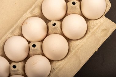 Beyaz kartondan yapılmış tepside beyaz tavuk yumurtaları, yakın plan seçici odak.