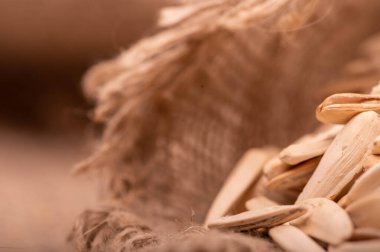 Beyaz ayçiçeği tohumları kaba bir çuval bezinin arka planına saçılmış, yakın çekim seçici odak