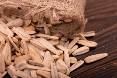 Beyaz ayçiçeği tohumları kaba bir çuval bezinin arka planına saçılmış, yakın çekim seçici odak