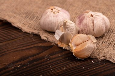 Çuval bezi kaplı bir masada bir sürü genç sarımsak, yakın plan, seçici odaklanma.