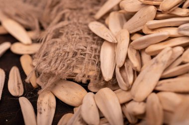 Beyaz ayçiçeği tohumları kaba bir çuval bezinin arka planına saçılmış, yakın çekim seçici odak