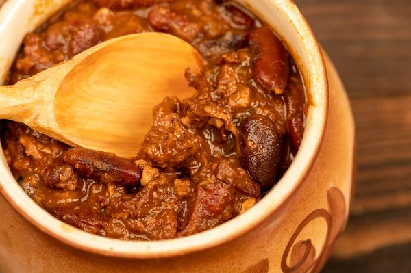 Stewed beans with meat in a small pot. A traditional rustic dish. Close-up, selective focus