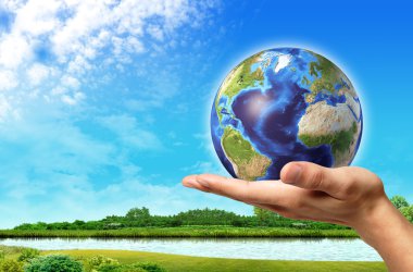 Man hand with earth globe on it and a beautiful green landscape clipart