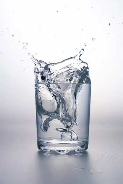 Wasserglas Mit Spritzer Auf Hellgrauer Oberfläche Und Weißem Hintergrund — Stockfoto