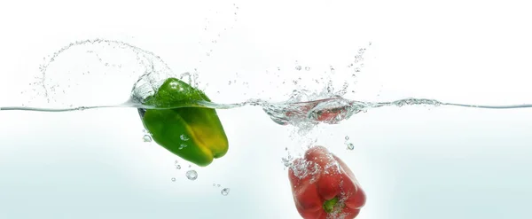 Two Peppers Green Red Splashing Water Side View White Background — Stock Photo, Image