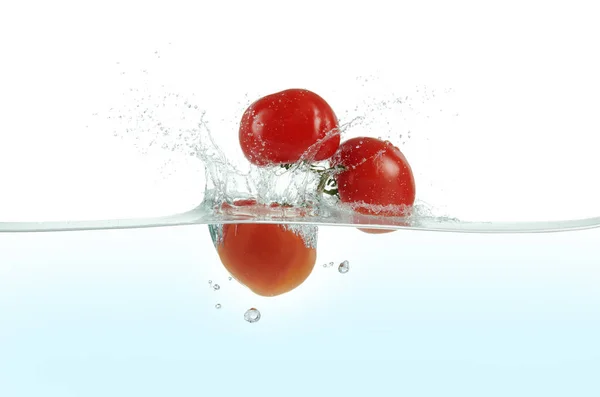 Trois Tomates Éclaboussant Dans Eau Photo De Stock