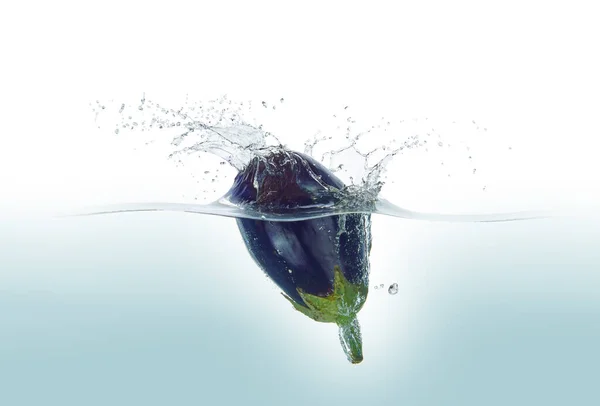 Aubergine splashing in water. Side view, on white background.