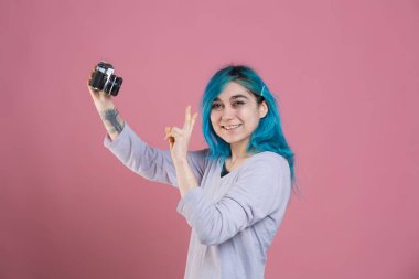 Genç bir kadın analog kamerasıyla selfie çekiyor.