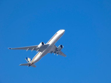 Mavi gökyüzünde uçan ticari yolcu uçağı