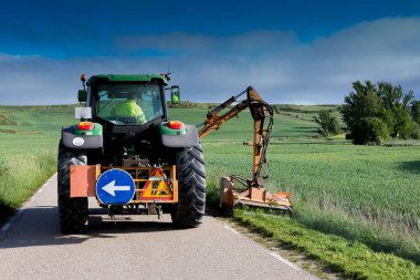 Orta İspanya 'da ilkbaharda otoyolda yabani otları temizleyen makine
