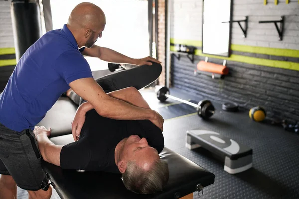 Männlicher Personal Trainer Und Physiotherapeut Unterstützt Ältere Rentner Beim Stretching Stockfoto