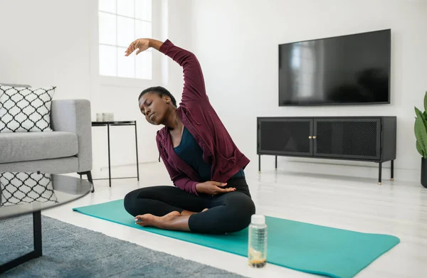 Close Black African Woman Sitting Stretching Yoga Pose Mat Living lizenzfreie Stockfotos