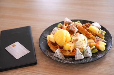 Dondurma, krem şanti ve çikolata soslu çikolatalı waffle. Üstten küçük kavanozla sulandırılmış. Tatlı soğuk Avrupa çileği, beyaz tabakta kivili tatlı.