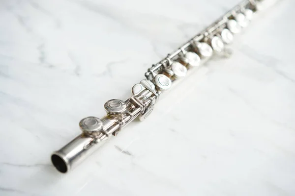 Flute, woodwind brass instrument in classical orchestra. Silver modern flute on white sheet music note for education and performance. Music instrument  for orchestra.