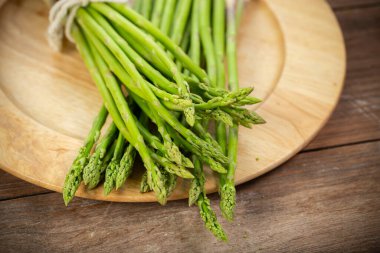 Kuşkonmaz yeşil ve düz sebzedir. Taze, yeşil kuşkonmaz ahşap masada tuzlu pişirmek için çıtır çıtır.