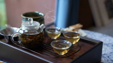 Geleneksel çay seti tepsisi, modern şeffaf tencere ve rahat Çin odasında temiz küçük bardak. Kurumuş yapraklı, doğal ve sağlıklı bir içecek güzel bir koku verir ve rahatlar..