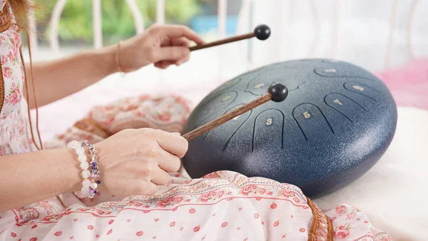 Steel drum playing with stick for hitting as percussion. Steel tongue drum is traditional African instrument as acoustic music for healing and therapy.