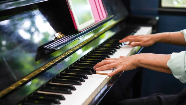 Adult woman plays electronic piano with note sheet. Professional pianist showing solo on acoustic black piano. practicing and learning how to play song. Classic instrument.