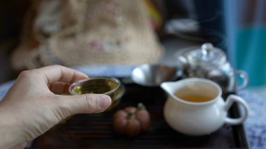 Bir fincan kahveyle çay seremonisi ve ahşap bir masada çaydanlık.