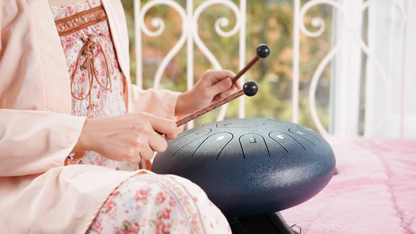 Steel drum playing with stick for hitting as percussion. Steel tongue drum is traditional African instrument as acoustic music for healing and therapy.