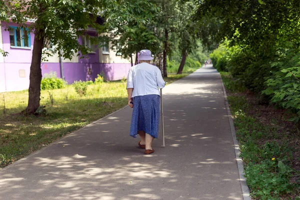 一个拿着手杖的老妇人在城里走来走去 — 图库照片