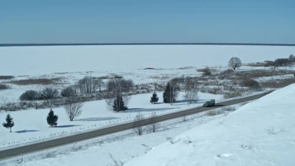 Bovenaanzicht vanuit de lucht vanaf de drone van het voertuig rijden op besneeuwde ijsweg — Stockvideo