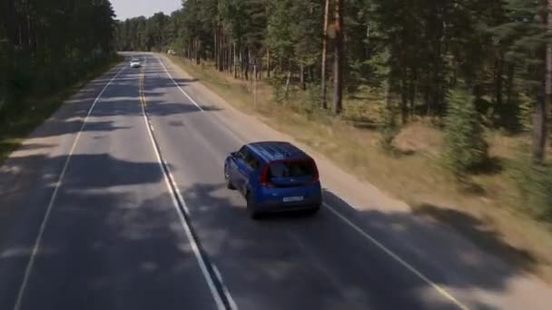 Niebieski samochód na drodze asfaltowej w okresie letnim. Widok z lotu ptaka. — Wideo stockowe