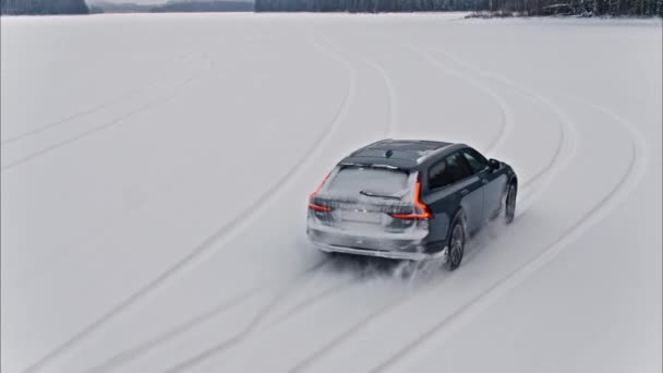 雪の湖で運転する灰色の駅ワゴン車のシネマティックショット. — ストック動画