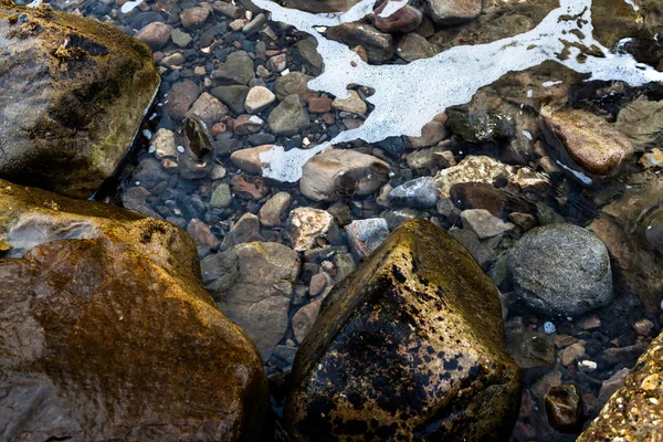 Skum på det klara vattnet nära klipporna — Stockfoto