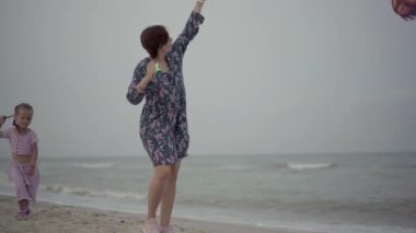 Küçük kızıyla birlikte deniz kıyısında uçurtma oynuyordu. Tek çocuklu mutlu beyaz bir aile deniz kıyısında yaz tatilinde eğleniyordu.