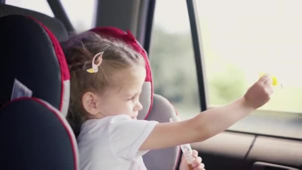 Маленькая девочка наслаждается мыльными пузырями во время езды на автомобиле — стоковое видео