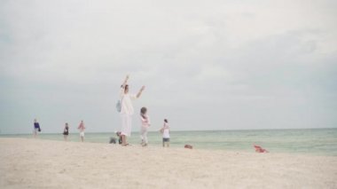 Küçük kızıyla birlikte deniz kıyısında uçurtma oynuyordu. Tek çocuklu mutlu beyaz bir aile deniz kıyısında yaz tatilinde eğleniyordu.