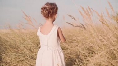 Sonbahar tarlasında dikiz aynasından bakan küçük kız beyaz çocuk yüksek otlarla oynuyor. Arka plan özgürlük kavramı orta çekim