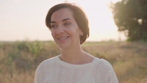 Tarım tarlasında duran kadın güz günü dişleri güneş ışığı arka planında gülümsüyor ağır çekim — Stok video