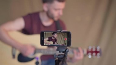 Öğrenciler için gitar dersleri kaydeden bir adam. Online gitar kursları. Uzaklık öğrenme kavramı Aygıt ekranına odaklan